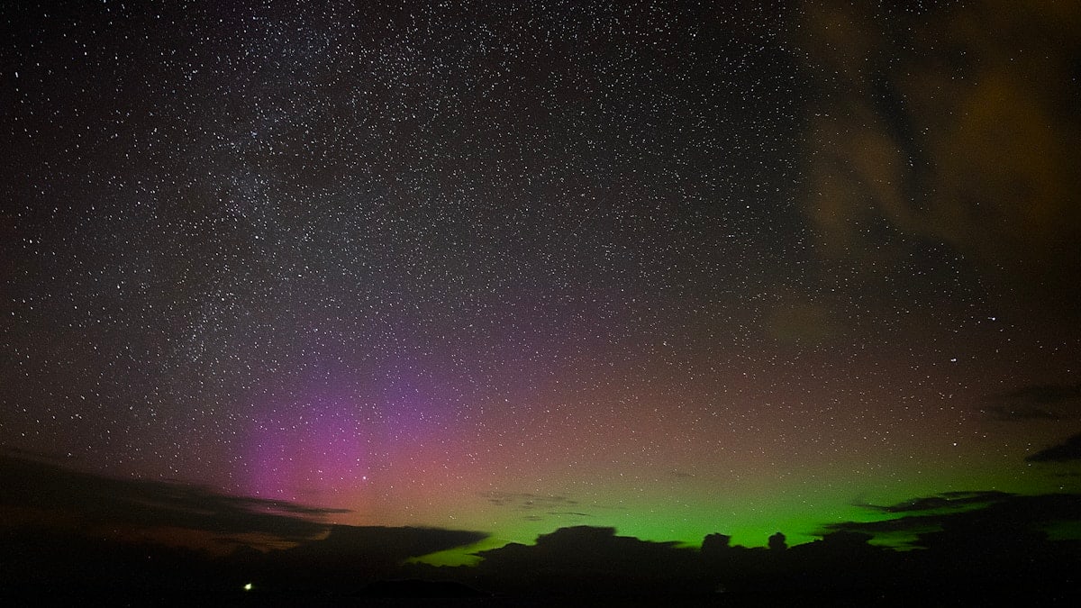 Aurora borealis lights up the starry night sky.
